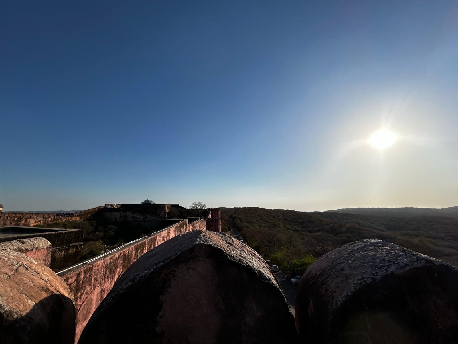 Late afternoon sun falling across stone fort walls and a wooded horizon